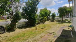 a yard with a fence and trees and a road at Green Getaway- Unique, 4 bedroom Bungalow Papakura in Auckland