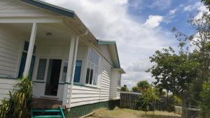 a white house with a porch and a fence at Green Getaway- Unique, 4 bedroom Bungalow Papakura in Auckland