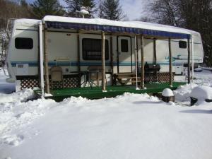 Una caravana estacionada en la nieve con nieve alrededor en Dark Ridge HideOut, en Elk Park