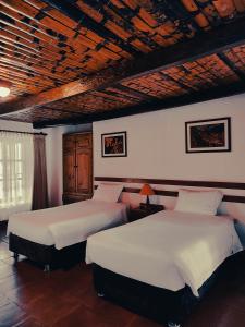 a bedroom with two beds and a wooden ceiling at Hotel Fundo Achamaqui in Chachapoyas