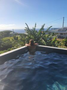 a woman in a swimming pool looking at the ocean at Cocon detente a Case pilote, chambre chez l'habitant in Case-Pilote