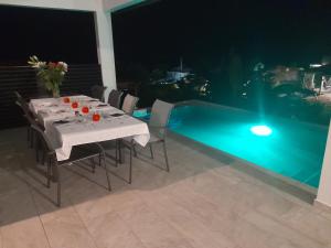 a dining table with chairs and a pool at night at Cocon detente a Case pilote, chambre chez l'habitant in Case-Pilote