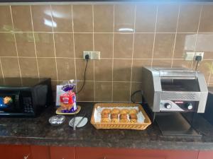 a kitchen counter with a microwave and a basket of pastries at The Sanctuary Langkawi in Pantai Cenang