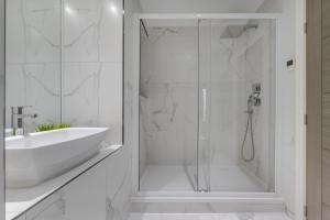 uma casa de banho branca com um chuveiro e um lavatório. em A Golden Haven Retreat in London em Londres