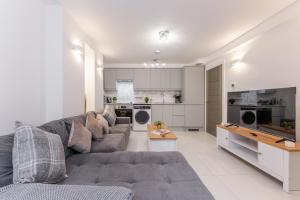 a living room with a gray couch and a kitchen at A Golden Haven Retreat in London in London