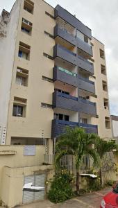 an apartment building with a palm tree in front of it at Apto mobiliado no Jardim Renascenca in São Luís