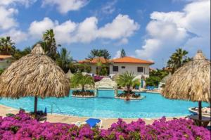 a swimming pool with umbrellas in a resort at Kas di BaMi A-194 op Seru Coral Resort - Ruim appartement met groot zwembad en tropische tuin in Willemstad