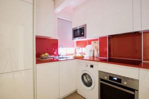 a kitchen with red and white cabinets and a washer at Apartamento moderno y céntrico en Huesca ciudad in Huesca