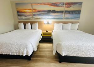two beds in a hotel room with paintings on the wall at Days Inn by Wyndham Ocala North in Ocala