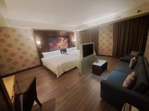 een hotelkamer met een bed en een bank bij Norway Forest Tamsui Motel in Tamsui