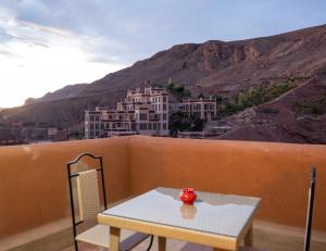 a table and chair on a balcony with a mountain at Riad Rihana Dades in Boumalne