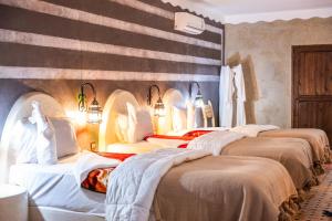 a group of four beds in a room at Riad Rihana Dades in Boumalne
