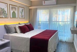 1 dormitorio con 1 cama blanca grande con almohadas rojas en Na praia - Araça 104 - Térreo frente mar, en Natal