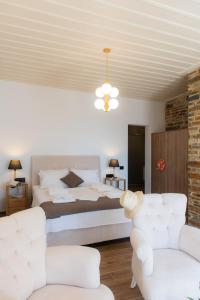 1 dormitorio con 1 cama y 2 sillas blancas en White & black Suites en Platís Yialós Sifnos