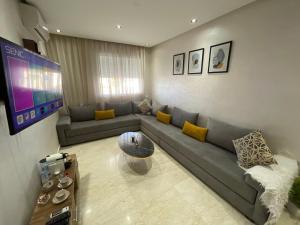 a living room with a couch and a tv at Appartement avec piscine - Mohammadia in Mohammedia