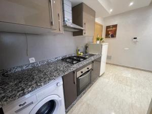 a kitchen with a washer and a sink and a dishwasher at Appartement avec piscine - Mohammadia in Mohammedia