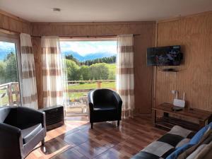 ein Wohnzimmer mit Sofa, Sesseln und einem Fenster in der Unterkunft Ventisca Sur in Coihaique