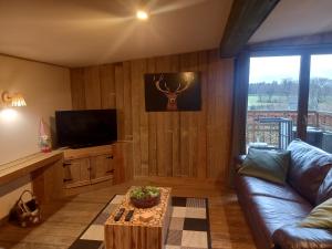 a living room with a couch and a tv at Le chalet du lac in Robertville