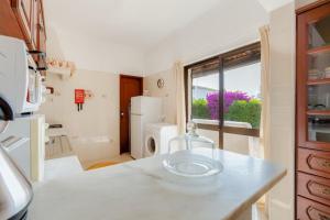 uma cozinha com um balcão branco e uma janela em VILLA ROSADO - Moradia para 6 com AC, jardim a 5 min do centro de Albufeira em Albufeira