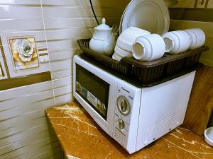 a microwave with plates and dishes on top of it at one-room apartment in Dushanbe in Dushanbe
