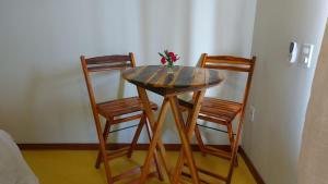 uma mesa de madeira com duas cadeiras e um vaso com flores em Recanto Berlin em Prado