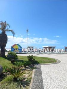 a sign in front of a beach with a palm tree at Apto POTY- 4 Pessoas - Ótima localização - 150 m do mar in Capão da Canoa