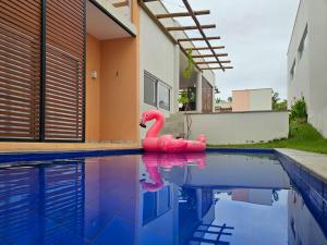 een roze flamingo zit in een zwembad bij Casa de alto padrão com piscina, ótima para grupos e famílias - a 300m do centro de Pipa in Pipa