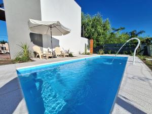 una piscina con ombrellone accanto a una casa di Los Carpinchos: Duplex a Federación