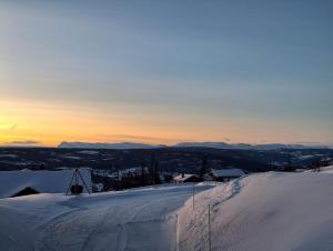 a snow covered hill with the sunset in the background at SPEGILL in Aurdal