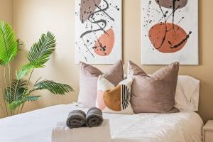 una camera da letto con letto bianco, cuscini e piante di Serene+Yard+Porch&EZ Bike2beach W/D+FreeParking a Signal Hill