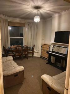 a living room with a piano and a dining table at Feel Like Your Home in Hastings