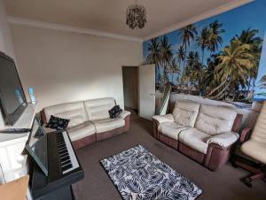 una sala de estar con 2 sofás y un piano en Feel Like Your Home en Hastings