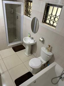 a white bathroom with a toilet and a sink at 56 Archer Crescent Mainhouse in Durban