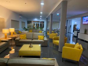 un vestíbulo con sofás, mesas y sillas amarillas en JP HOUSE en Nelas