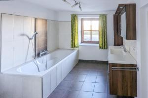 La salle de bains blanche est pourvue d'une baignoire et d'un lavabo. dans l'établissement Private Farmhouse Escape - Ideal for up to 8 Guests, à Seeham
