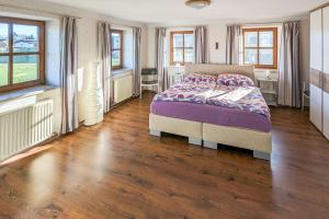 a bedroom with a bed and wooden floors and windows at Private Farmhouse Escape - Ideal for up to 8 Guests in Seeham