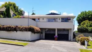 a white house with a garage in front of it at Park View 'Home Away From Home' in Feilding