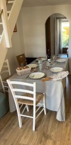 einen weißen Tisch mit Stühlen und einen Tisch mit Tellern in der Unterkunft Maison climatisé 2 chambres 700 m de la mer avec parking gratuit in Saint-Cyprien