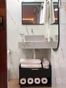 a bathroom with a sink and a mirror and towels at Suíte Verão na Praia in Cabo Frio