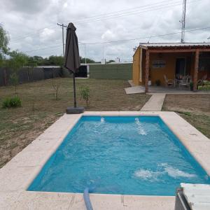 una piscina con sombrilla en un patio en Casa de Campo Atenea en Santiago del Estero