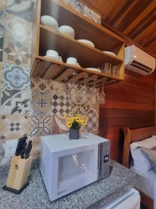 a kitchen with a microwave on a counter at Chalé Faisão Recanto Buscapé SFX in São Francisco Xavier