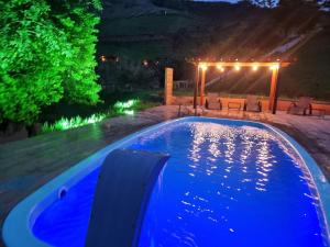 a swimming pool in a backyard at night at Chalé Faisão Recanto Buscapé SFX in São Francisco Xavier