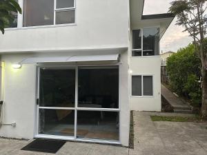 una casa bianca con una grande porta scorrevole in vetro di The Explorers Atelier ad Auckland