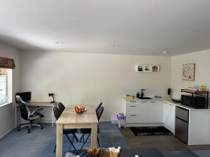 uma cozinha com mesa e cadeiras e uma secretária em New Lynn Self- Contained Unit near Golf Course em Auckland