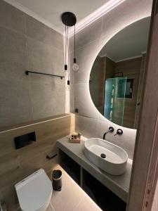 een badkamer met een wastafel, een toilet en een spiegel bij Olive-Luxury apartment in agrinio in Agrinion