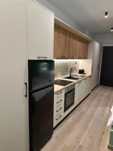 a kitchen with a black refrigerator and white cabinets at Olive-Luxury apartment in agrinio in Agrinion