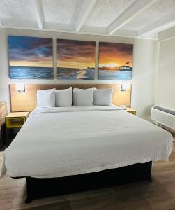 a bedroom with a large bed with two paintings on the wall at Days Inn by Wyndham Ocala North in Ocala