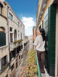 a woman standing on a balcony looking out of a building at Hinc Domus - Venezia Historical City Center in Venice