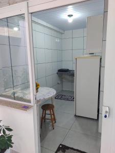 a kitchen with a refrigerator and a table and a stool at Residencial Caiobá I in Matinhos