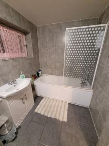 a bathroom with a bath tub and a sink at Cozy room London in Enfield